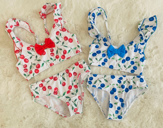 Bikini bambina fantasia ciliegie rosse e blu con fiocco centrale e spalline arricciate, taglia 2-12 anni.